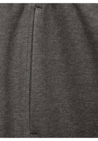 Tissu gris à la texture lisse, avec un détail de couture vertical et une finition légèrement brillante, indiquant un matériau doux et extensible.