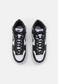 Black and white high-top sneakers with a leather upper, round toe, perforated toe box, and black laces. Nike logo on the tongue.