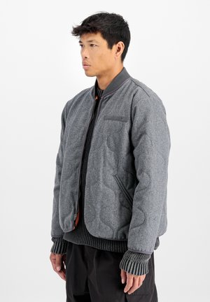 Chaqueta bomber acolchada gris con puños y cuello de canalé, que cuenta con cierre de cremallera y bolsillos laterales, elaborada en un suave material de mezcla de lana.