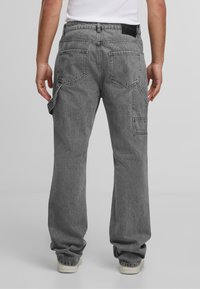 Graue Cargo-Hosen mit lockerer Passform, mehreren Taschen und einem verblassten Material. Besitzt einen Bund mit einem Markenlabel und umgekrempelte Säume.