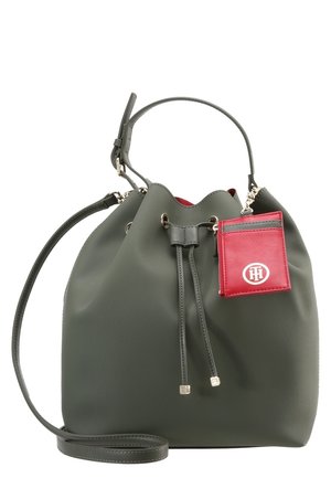 Sac seau en cuir vert foncé avec fermeture à cordon, anse unique, longue bandoulière et un petit porte-cartes rouge attaché avec un logo blanc.