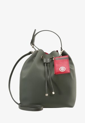 Donkergroene leren bucketbag met trekkoordsluiting, enkele handgreep, lange schouderriem en een klein bevestigd rood kaarthoudertje met een wit logo.