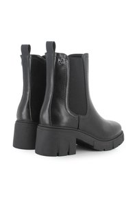 Botas negras hasta el tobillo con un acabado de cuero suave, paneles laterales elásticos y una suela de goma gruesa. Incluye un tacón reforzado y un detalle de logo.