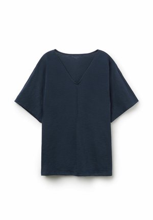 Top suelto de manga corta y cuello en V de color azul oscuro, con un tejido sutilmente texturizado y una costura que corre por el centro delantero.