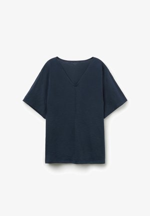 Top suelto de manga corta y cuello en V de color azul oscuro, con un tejido sutilmente texturizado y una costura que corre por el centro delantero.