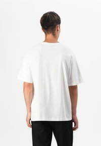 White cotton t-shirt with a relaxed fit, short sleeves, and acrew neckline. Smooth texture and no visible patterns or accents.