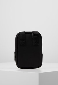 Borsa nera rettangolare realizzata in tessuto resistente, dotata di due manici superiori, chiusura con zip e superficie liscia.