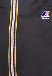 Geacă neagră cu fermoar, având o dunga verticală multicoloră ce include alb, galben, portocaliu și bleumarin. Logo-ul K-Way pe partea superioară stângă. Textură netedă.