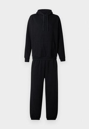 Svart hoodie med framficka och matchande svarta mjukisbyxor med elastisk mudd visas på vit bakgrund.