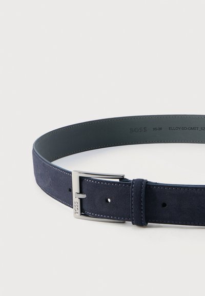 Ceinture en daim bleu marine avec boucle rectangulaire argentée gravée de "BOSS", présentant des bords cousus et des indications de taille à l'intérieur.