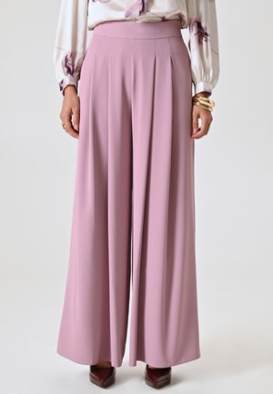 Pantalons large rose pâle avec un devant plissé, en tissu doux. Dotés d'une taille élastique haute et d'une silhouette fluide.