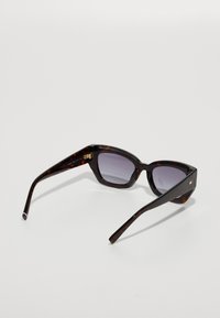 Ochelari de soare cu ramă din scoică, cu un cadru geometric, lentile gri cu gradient și accesorii aurii pe arms. Finisaj neted și lucios.