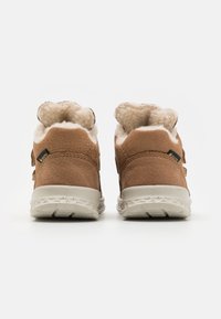 Bottes en daim marron avec une doublure en fourrure blanche douce et une semelle en caoutchouc blanche. Comprend deux sangles réglables pour un ajustement sécurisé.