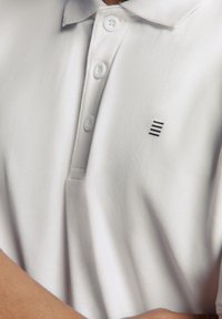 Witte polo shirt van textiel met een gestructureerde stof, met een tweeknoopssluiting en een klein zwart logo op de linkerborst.