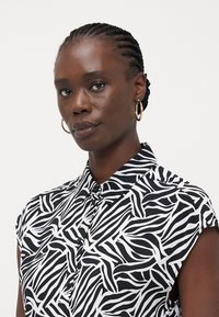 Μαύρο και άσπρο κοντομάνικο πουκάμισο με φύλλα, με κλείσιμο με κουμπιά και απαλό υφασμά.