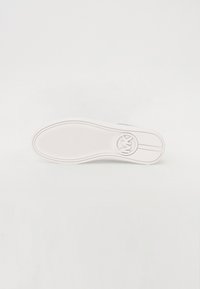 Fehér sneaker talp texturált anyagból, középen kör alakú logóval és két párhuzamos vonallal. Sima felület és lekerekített orr forma.