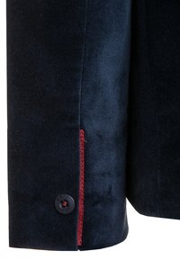 Mörkblå sammetjacka med ärm som har en röd dekorativ söm och en svart knapp med präglad text. Slät textur, skräddarsydd passform.