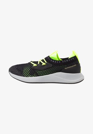 Černá síťová sportovní bota s neonově zelenými akcenty, s silnou bílou podrážkou, elastickými tkaničkami a logem Under Armour na pásku.