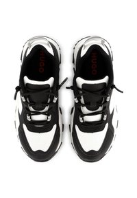 Sneaker in bianco e nero con tomaia in rete, dettagli testurizzati e suola in gomma spessa. I lacci sono fissati con hardware a toggle.