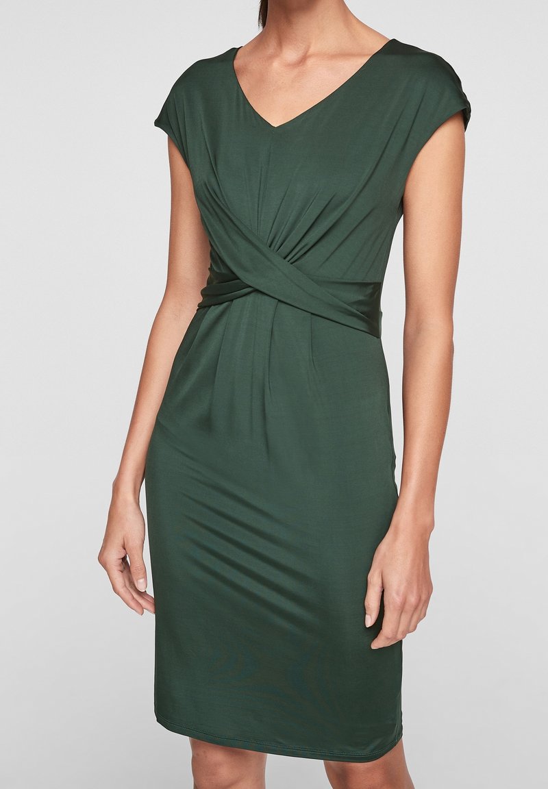 Mörkgrön figurnära klänning med V-ringning, korta ärmar och vridningsdetalj vid midjan; slät textur och knälång design.