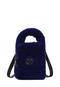 Pequeño bolso de mano azul marino de peluche con un asa superior, una correa para el hombro ajustable negra y un logo metálico redondo con un charm de llavero.