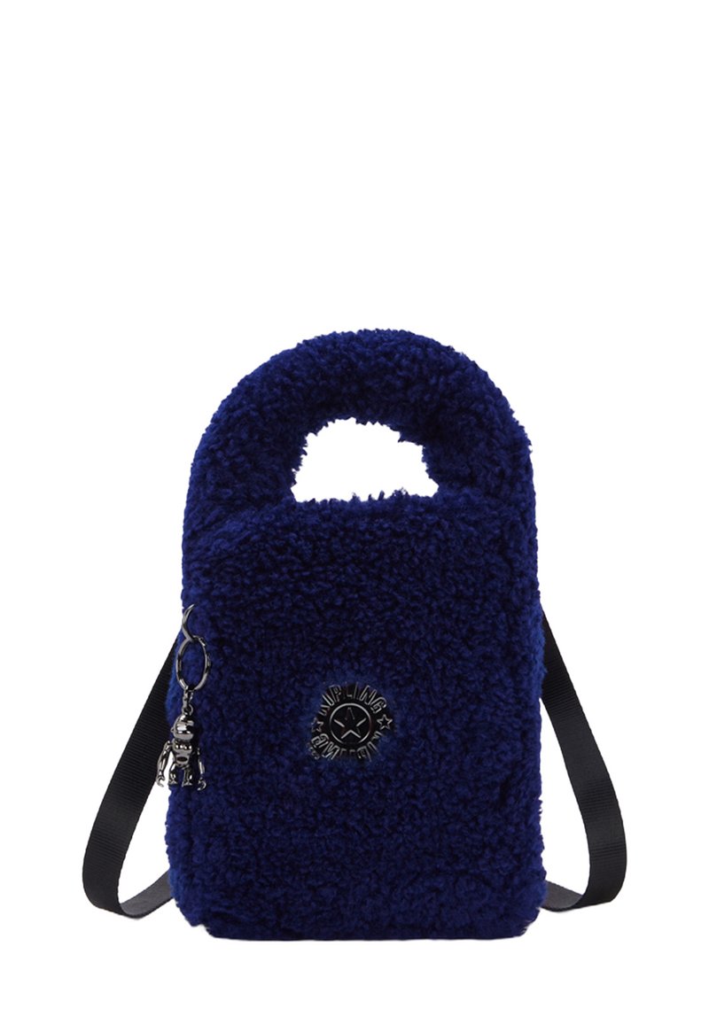 Pequeño bolso de mano azul marino de peluche con un asa superior, una correa para el hombro ajustable negra y un logo metálico redondo con un charm de llavero.