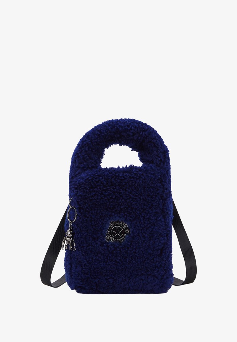 Pequeño bolso de mano azul marino de peluche con un asa superior, una correa para el hombro ajustable negra y un logo metálico redondo con un charm de llavero.