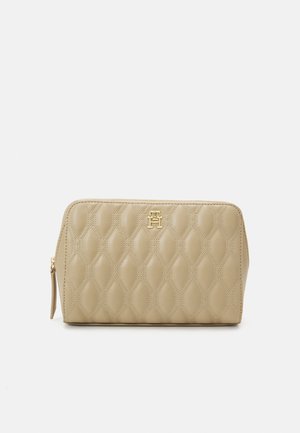 Beige quiltet kosmetikpose med et guld logo, lynlås-lukning og struktureret mønster. Rektangulær form med afrundede kanter.