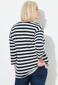 Gestreiftes Langarmtop mit marineblauen und weißen Horizontalstreifen, lockerer Passform, weichem Stoff und abgerundetem Saum. Kombinieren Sie es mit dunklen Jeans.