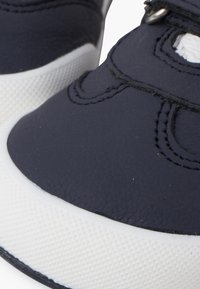 Námořnické kožené tenisky s texturovanými bílými gumovými podrážkami, s prošívanými detaily a bezpečným suchým zipem pro nastavitelné uchycení.