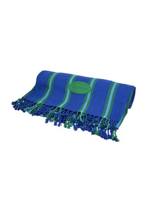 Niebiesko-zielony prążkowany ręcznik tkany z frędzlami na brzegach i owalną zieloną naszywką z logo „havaianas”, złożony na białym tle.