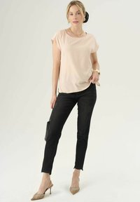 Svetloružový krátky rukáv s okrúhlym výstrihom, v kombinácii s čiernymi slim-fit džínsami a béžovými lodičkami so špicatou špičkou. Čierna kabelka.