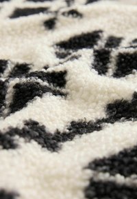 Gros plan d'un tissu texturé noir et blanc avec un motif en boucle doux formant des formes abstraites.
