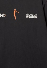 Musta puuvillane T-särk, mille keskel on oranž siluett ja selle all valged tähed "IMAGINE DRAGONS". Pehme ja sile tekstuur.