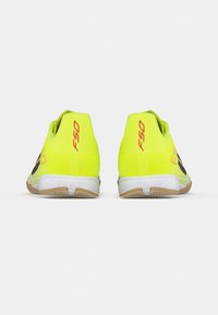 Φωτεινά κίτρινα ποδοσφαιρικά παπούτσια με μαύρες λεπτομέρειες, διχτυωτό πάνω μέρος και υφασμένο λαστιχένιο πάτο· διαθέτουν χαμηλό προφίλ σχεδιασμού για ευκινησία.