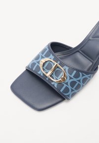 Sandale à glissière bleu marine avec une sangle en tissu à motifs et un accent de boucle dorée. Le design à bout carré présente une texture de semelle lisse.