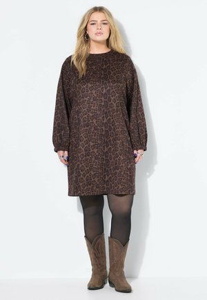 Bruine panterprint jurk met lange mouwen, losse pasvorm en ronde halslijn. Draag je over zwarte panty’s en bruine cowboylaarzen.