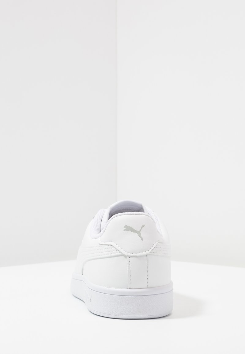 Baskets blanches avec une tige en cuir lisse, un talon arrondi et un logo argenté à l'arrière. Détails texturés sur les côtés.