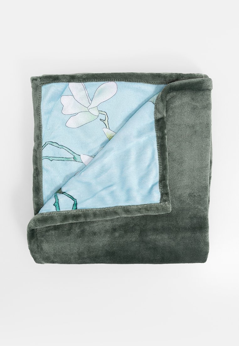 Couverture en peluche douce, avec un extérieur vert menthe et un intérieur bleu clair orné d'un motif floral. Les bords sont finis avec un tissu assorti.