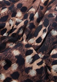 Tissu avec une texture froissée et un motif léopard marron, noir et beige.