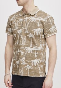 Kortsleeve brun polo shirt med hvit palmetre- og surfebrettmønster, beige krage og mansjetter, tre knappåpninger, teksturert stoff.