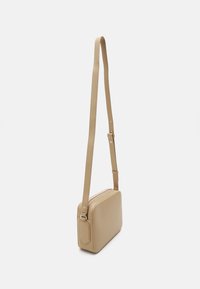 Borsa a spalla in pelle beige con forma rettangolare, tracolla regolabile e chiusura con zip, caratterizzata da una texture liscia e un design minimalista.