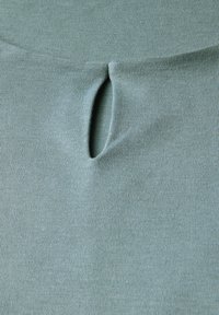 Top de tejido acanalado verde claro con escote redondeado y detalle de corte en forma de llave en el centro. Textura suave y diseño ajustado.