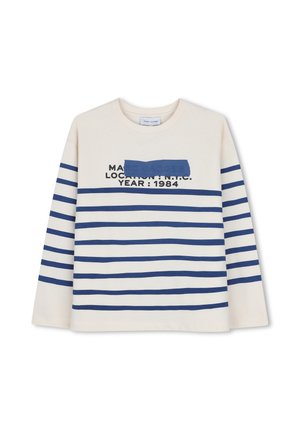 Chemise crème à manches longues avec des rayures horizontales bleu marine et un texte lisant "LOCATION : N.B.C. YEAR : 1984", partiellement recouvert par un bloc bleu marine.
