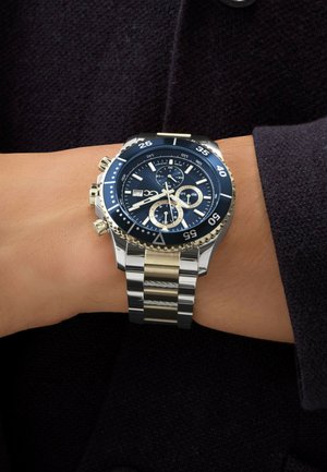 Chronograph watch with a blue dial, silver and gold stainless steel strap, and a rotating bezel. Features sub-dials and date display.