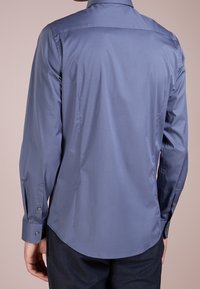 Herenoverhemd met lange mouwen in effen lichtblauw, voorzien van een rechte snit, gladde textuur en manchetten met knopen en een afgeronde zoom.