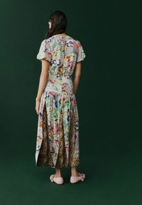 Abito maxi con stampa floreale in colori vivaci, orlo arricciato e accenti a stampa leopardata. Maniche corte e dettaglio sul busto aderente.