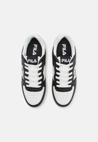 Black and white athletic shoes with a smooth leather upper, round toe, perforation details, white laces, and a logo on the tongue.