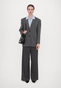 Gray pinstripe oversized blazer with a blue collared shirt, wide-leg trousers, and a small black handbag with a chain handle.