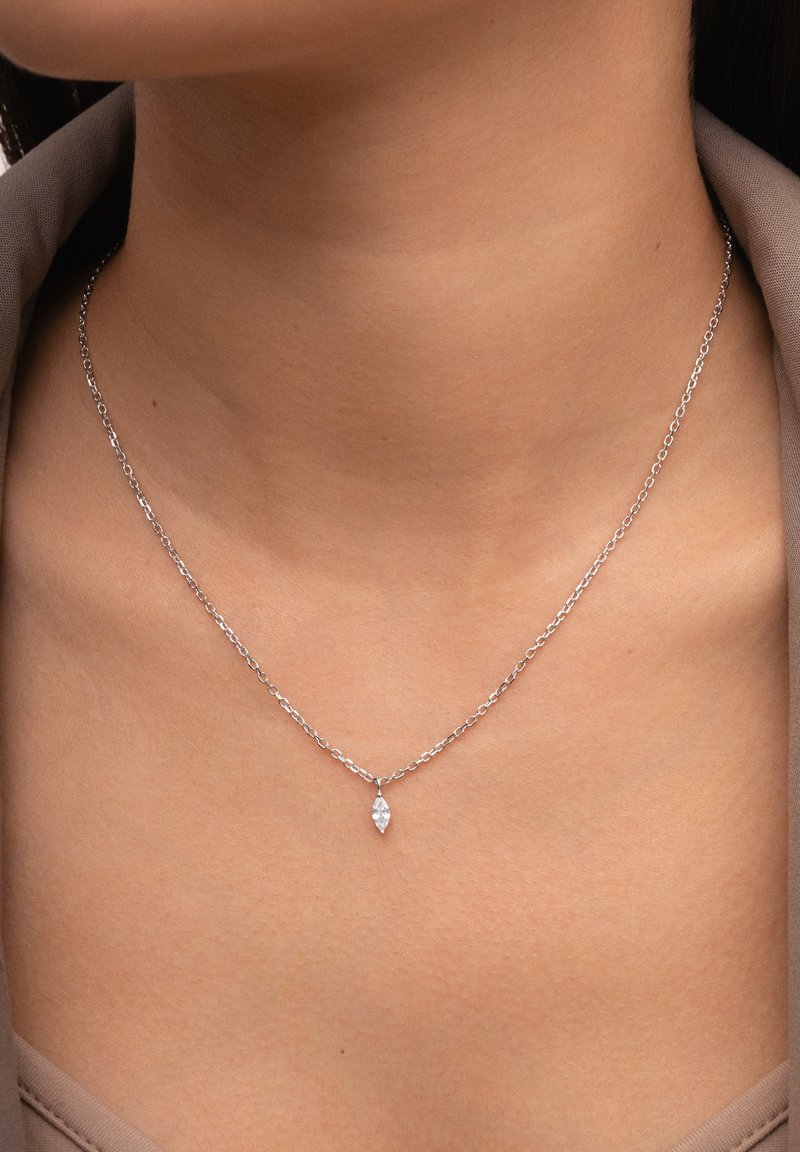 Collana in argento con un ciondolo allungato a forma di marquise con una pietra trasparente, che poggia delicatamente sulla clavicola.